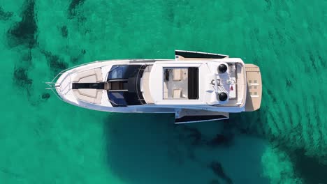 Top-down-drone-shot-of-yacht-in-crystal-clear-water-in-the-mediterranean-sea