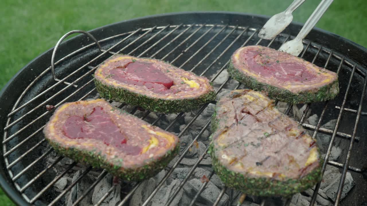 다진 고기와 체다 치즈로 덮인 스테이크가 그릴에서 요리되고 있습니다.