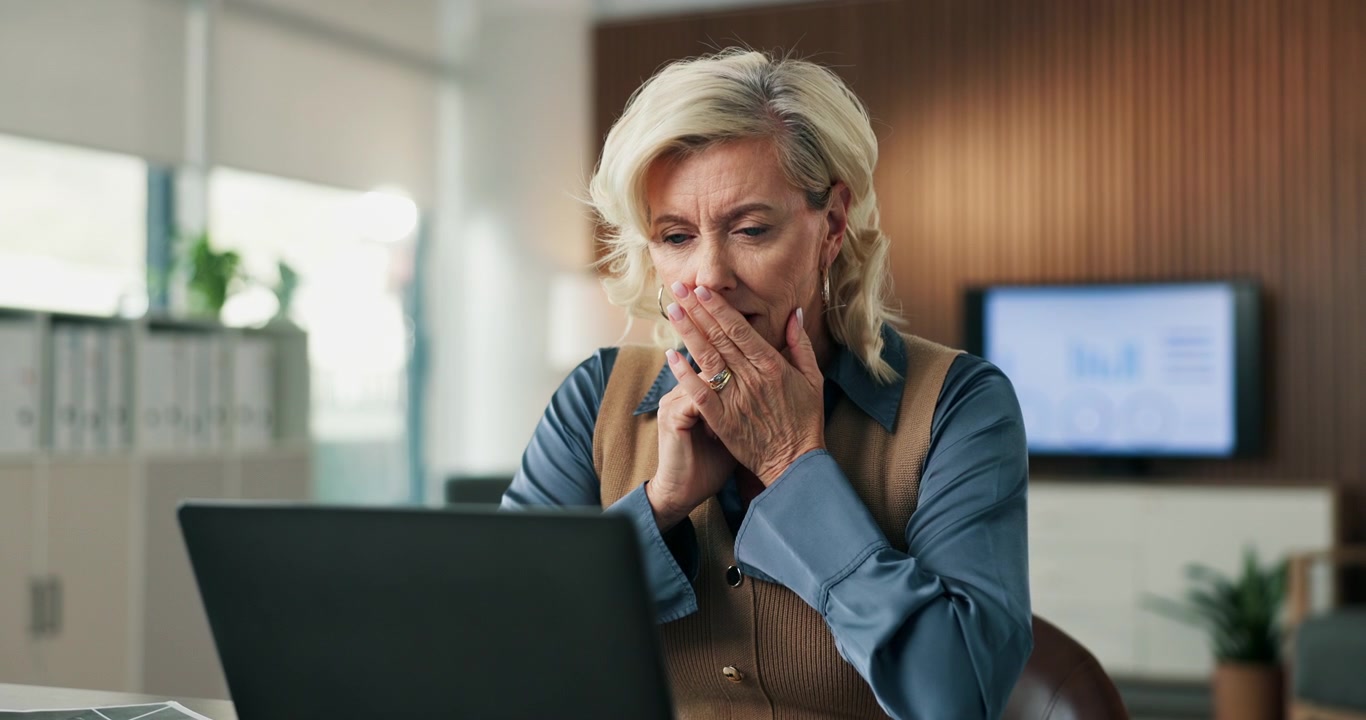 Mature Businesswoman Reacting With Shock While Working on Laptop