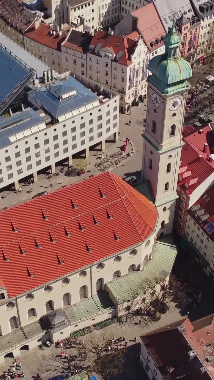 Downtown streets and Heilig Geist church with tower in Munich, aerial view