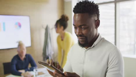 Portrait-of-happy-african-american-businessman-with-tablet-in-creative-office