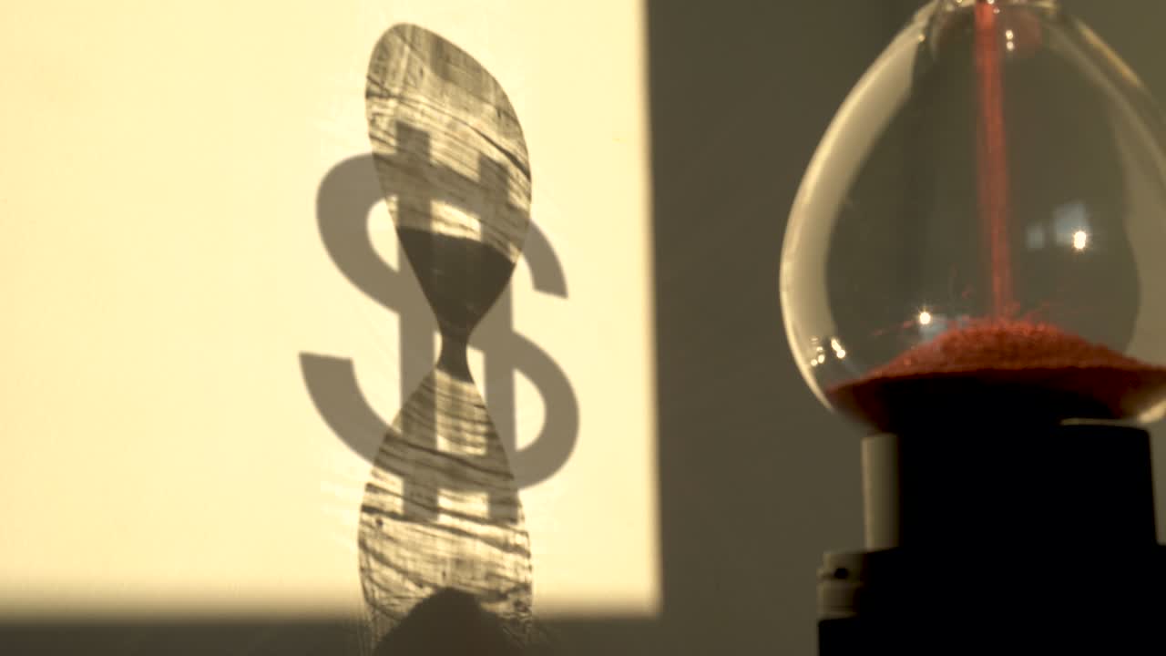 reloj de arena con la sombra de un signo de dólar en el fondo