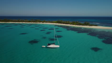 aerial parallax around sailboat anchored in calm cove off small island, isle of pines