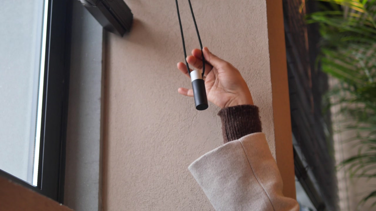 Person's Hand Adjusting Window Blinds by Pulling Cord