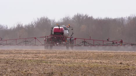 vehicle spraying farmland with a liquid herbicide and pesticide on a crop field