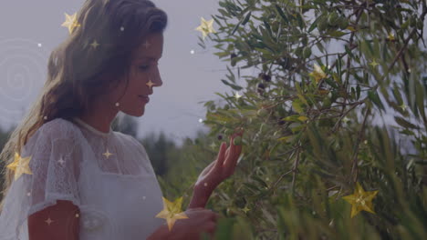 woman gently touching olive branches, with animated golden stars and spiral lights for agriculture