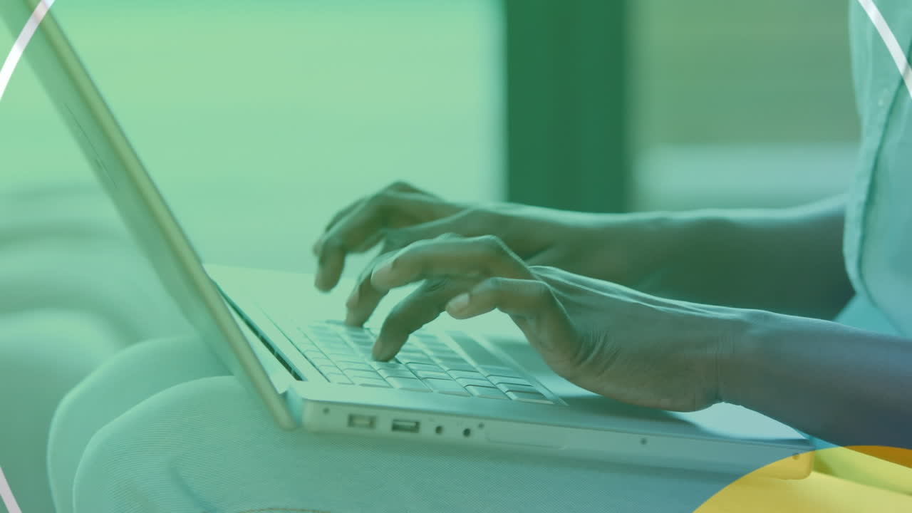 Animation of shapes over african american man using laptop