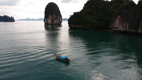 imágenes de drones de un bote de cola larga navegando alrededor de las islas de tailandia con las formaciones rocosas de piedra caliza que sobresalen del agua y el océano en el fondo-4