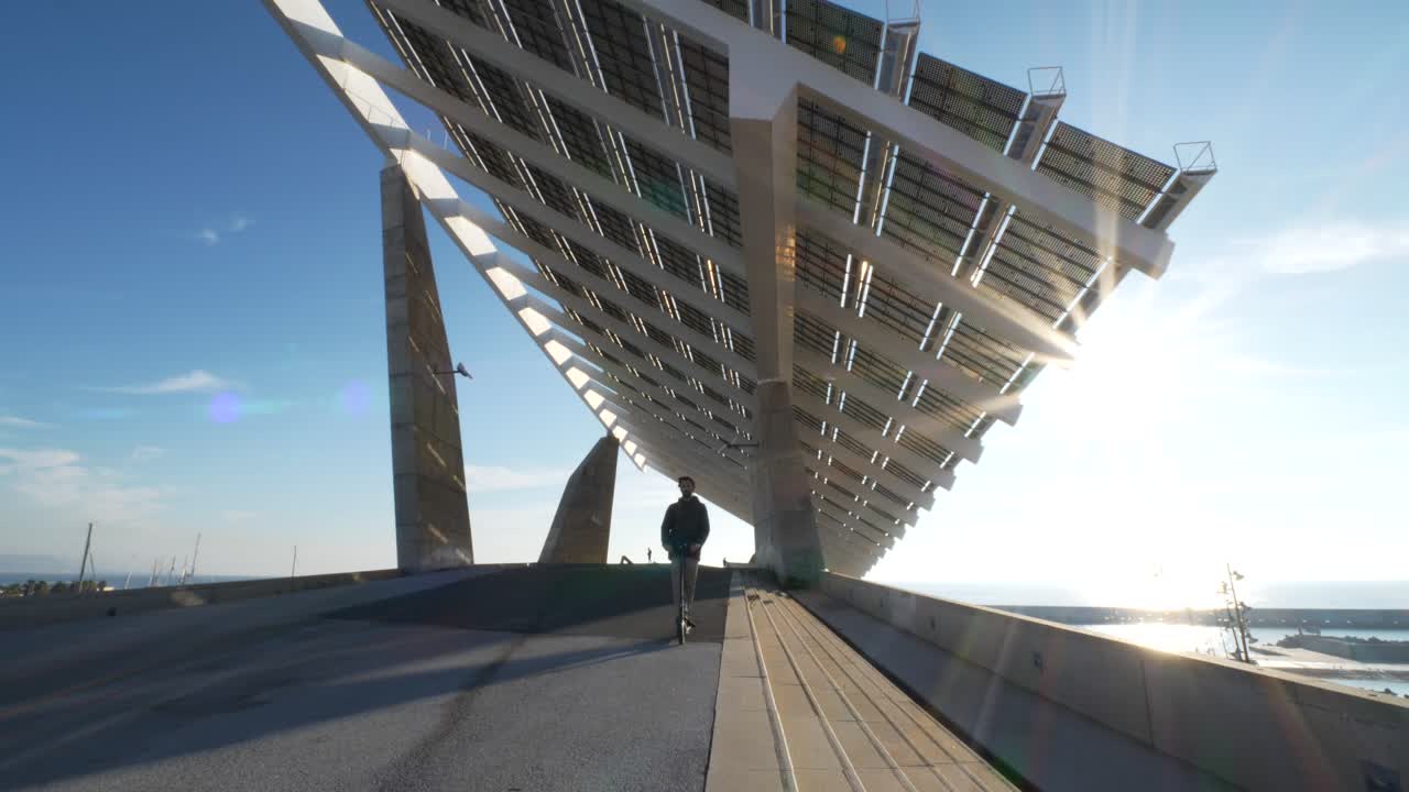 macho joven montando bajo un panel solar en scooter eléctrico city street concepto solar energía verde