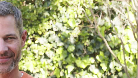 Half-face-of-happy-caucasian-man-standing-and-smiling-in-sunny-garden