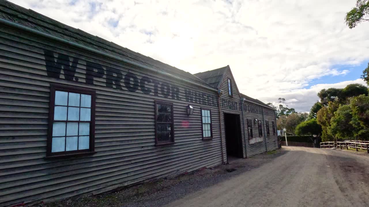 A camera pans along a historic building in Ballarat, capturing its rustic architecture and surrounding greenery under a bright sky