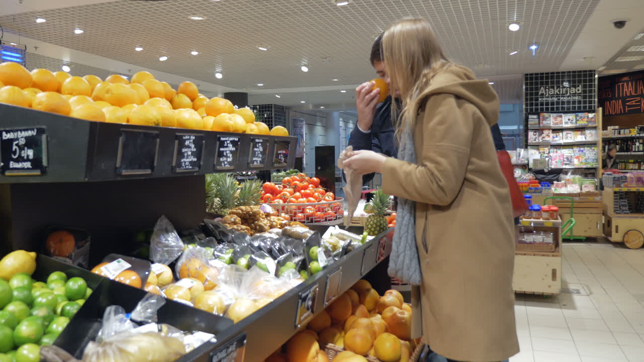 una pareja feliz eligiendo naranjas en el supermercado.