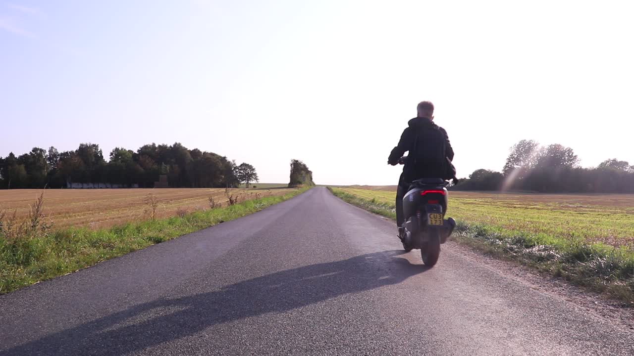 Dark scooter drives by, Scandinavia.