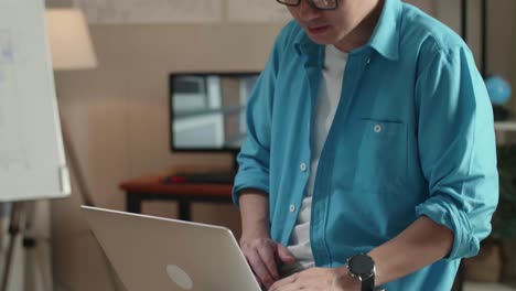 close up of asian man engineer sitting on the table and using a laptop to work at the office