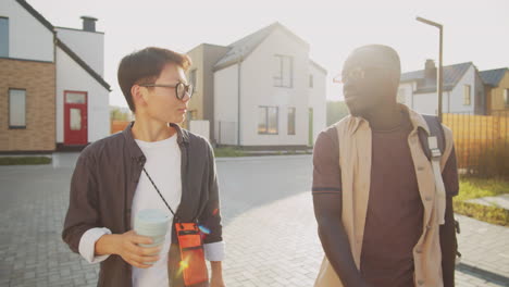 young black man and asian woman walking on street and speaking