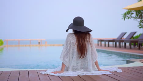 woman in summer outfit sitting by the swimming pool