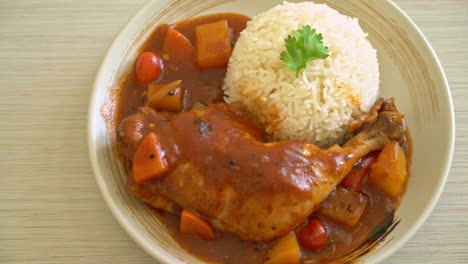 homemade chicken stew with tomatoes, onions, carrot and potatoes on plate with rice