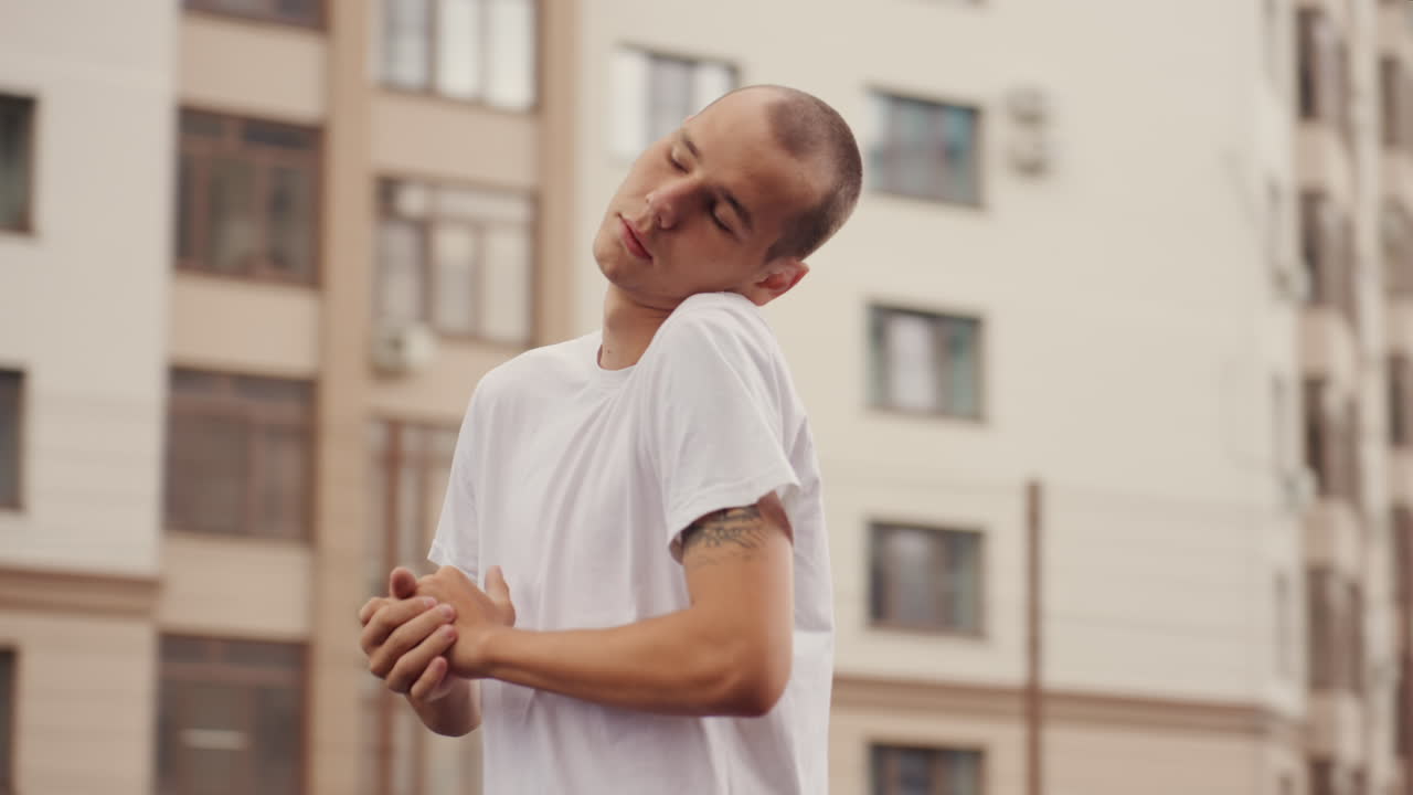 Retrato de un hombre blanco en una azotea con una camisa mojada, figura empapada con el antebrazo tatuado, cabeza inclinada hacia atrás bajo un cielo nublado, mirada introspectiva, gotas de lluvia sobre la piel, edificios altos al fondo, cinematográfico