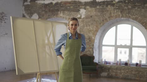 portrait smiling woman wearing apron to start painting in workshop