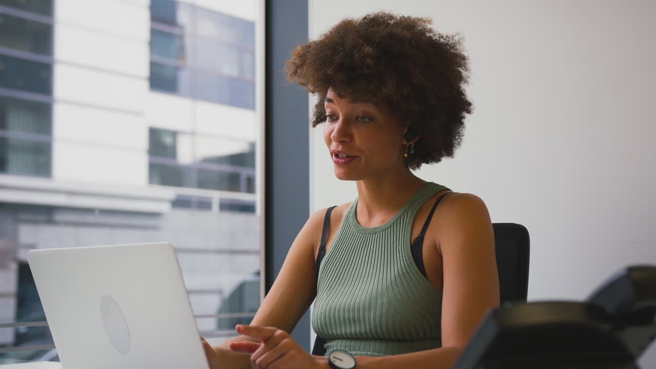 Businesswoman In Modern Office Working At Desk Making Video Call On Laptop
