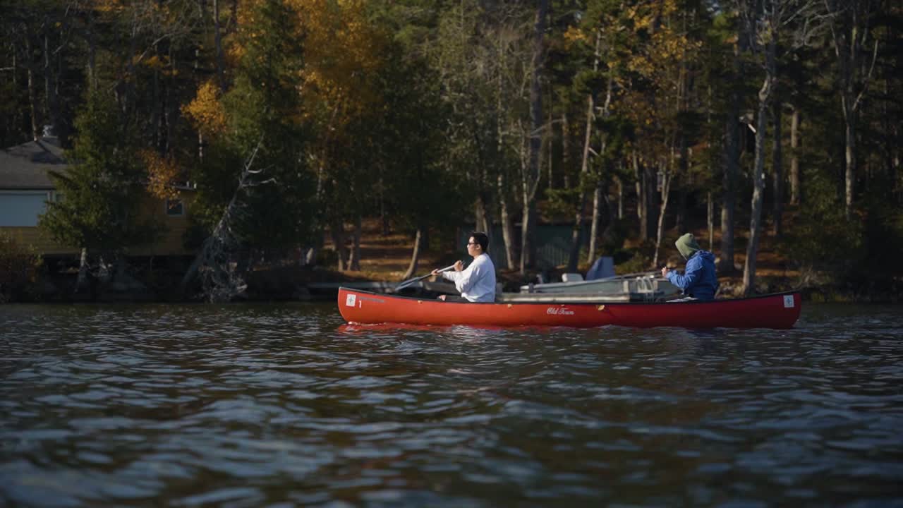 Two young men paddling a canoe in the autumn season on a lake