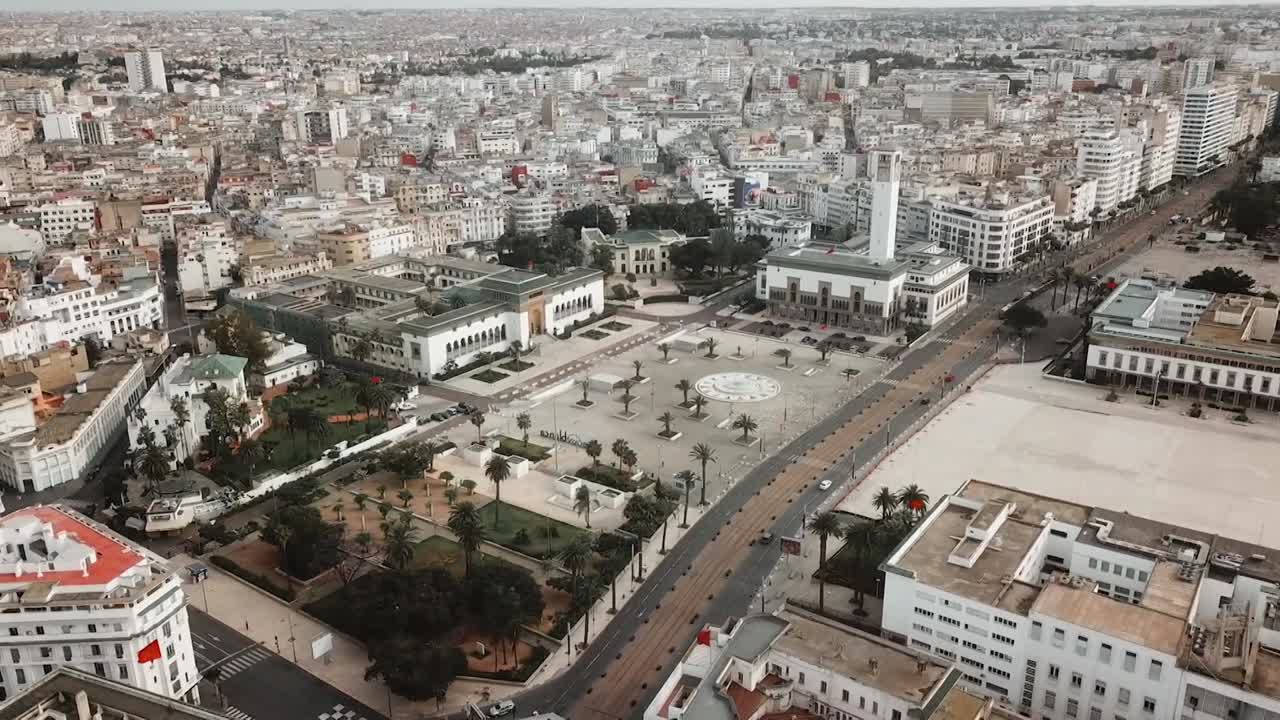 Panoramic aerial drone view of Casablanca's central administrative district. Highlights the historic city hall with its iconic clock tower, the public square, and the dense urban grid