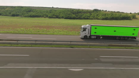 white truck with green screen trailer on highway