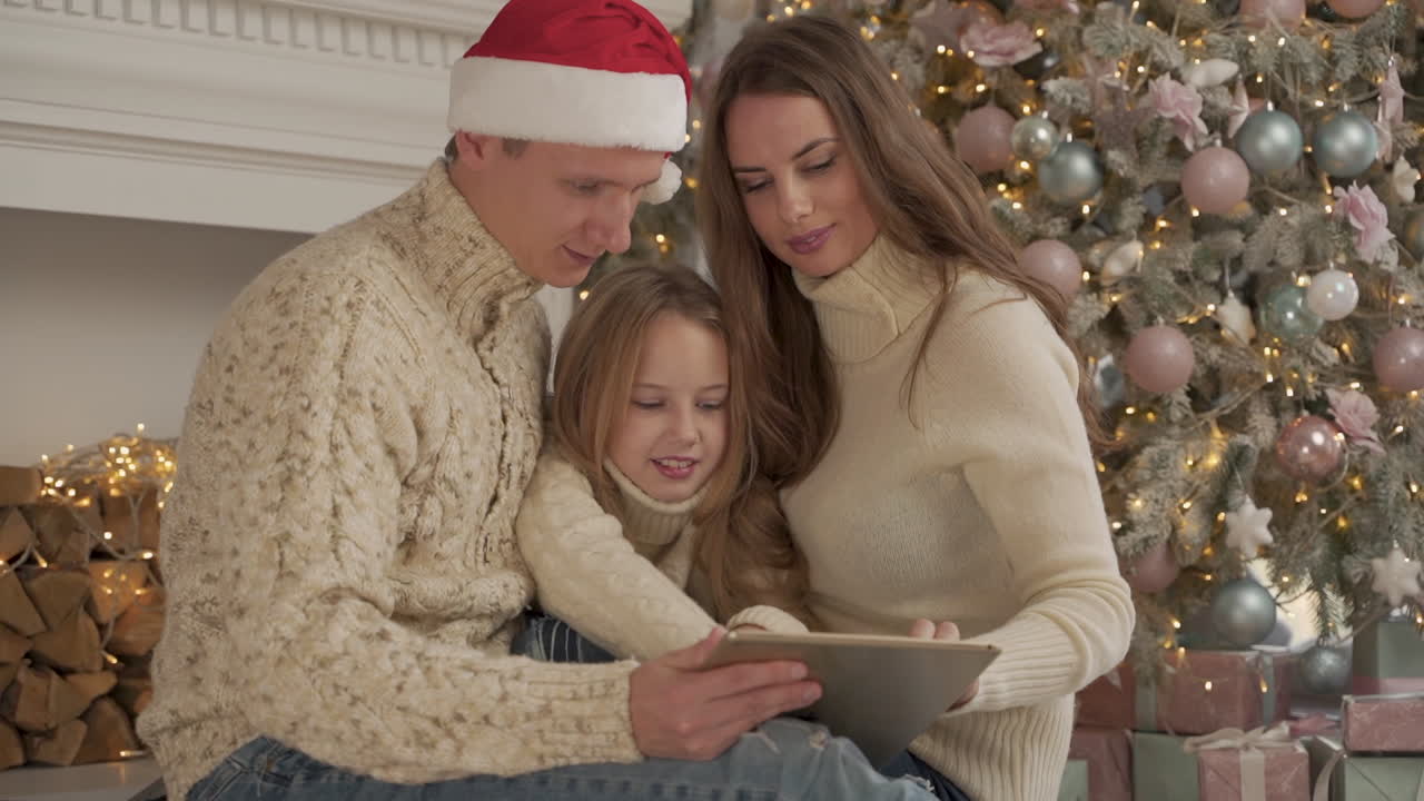 familia feliz jugando con una tableta en navidad usando un sombrero de santa 1