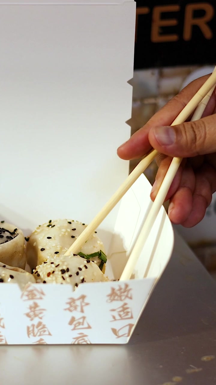 Mão usando pauzinhos para pegar dim sum.