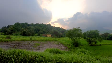 Una-Hermosa-Vista-De-Una-Montaña-Cerca-De-Un-Pequeño-Pueblo-Y-Granja-Y-Un-Pequeño-Lago-|-Hermoso-Bosque-Verde-En-Maharashtra,-India-Temporada-De-Monzones-Fondo-Con-Paisaje-De-Nubes-Tormentosas