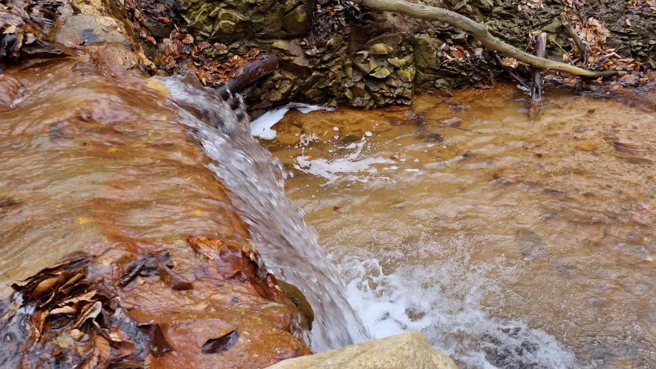 cascada de un arroyo de agua de riachuelo en el bosque en un día de invierno