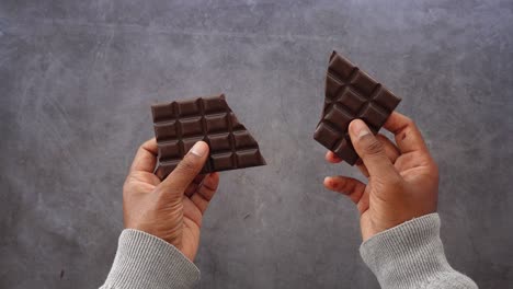broken dark chocolate bar in hands