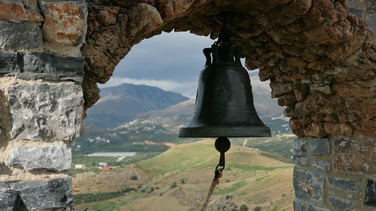 Sino de igreja antigo com moldura de pedra e fundo de vista para montanhas e colinas