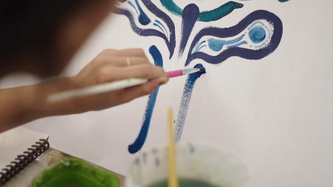 Close-up of a person painting an abstract design on canvas