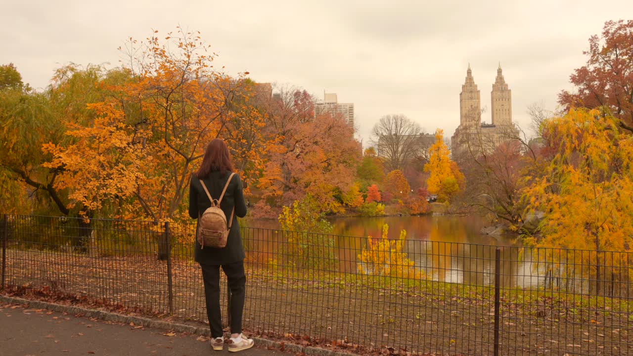 Woman enjoys fall in Central Park, NYC, surrounded by vibrant autumn colors