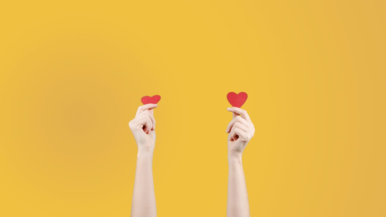 blogger mujer sostiene en la mano un pequeño corazón rojo en fondo amarillo naranja. como en la red social. día de san valentín, día internacional de la mujer, amor