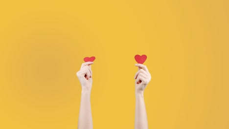 blogger mujer sostiene en la mano un pequeño corazón rojo en fondo amarillo naranja. como en la red social. día de san valentín, día internacional de la mujer, amor