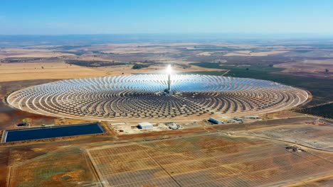 vista aérea con un dron de una planta solar térmica grande y circular utiliza espejos que enfocan los rayos solares en una torre de recolección para producir energía renovable y libre de contaminación - concepto ambiental