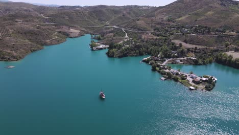 vista aérea por encima de un barco turístico navegando en las brillantes aguas turquesas del lago verde en las montañas tauro de turquía
