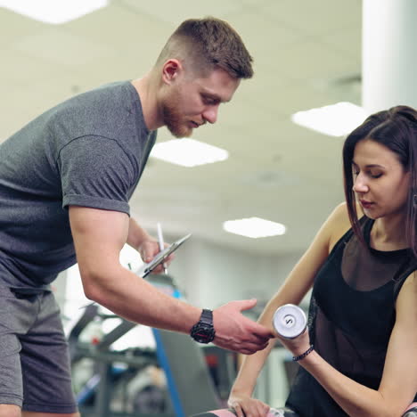 young and beautiful woman working out with dumbbells in gym. personal fitness instructor. personal training.