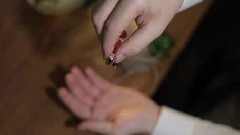 el novio con una camisa blanca deja caer los anillos de bodas en la palma de su mano. el hombre toca los anillos