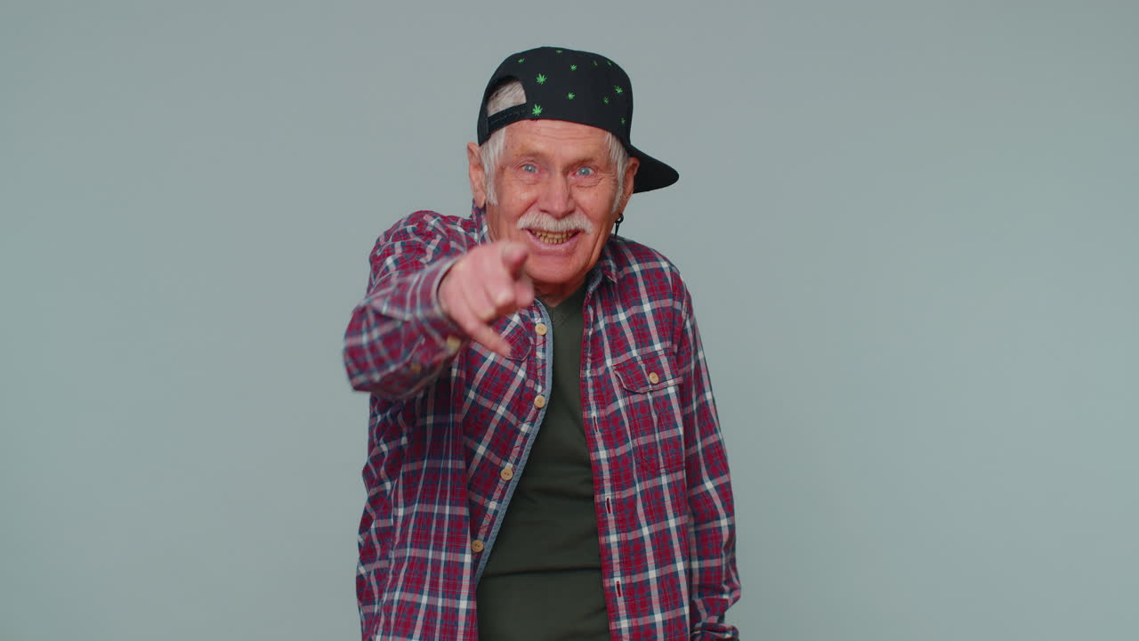 hombre señalando con el dedo a la cámara, riendo en voz alta, burlándose de la apariencia ridícula, broma divertida