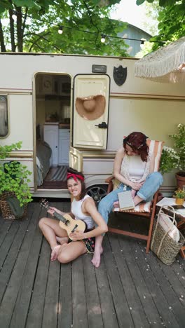 two friends enjoying a summer day on a wood deck next to a campervan