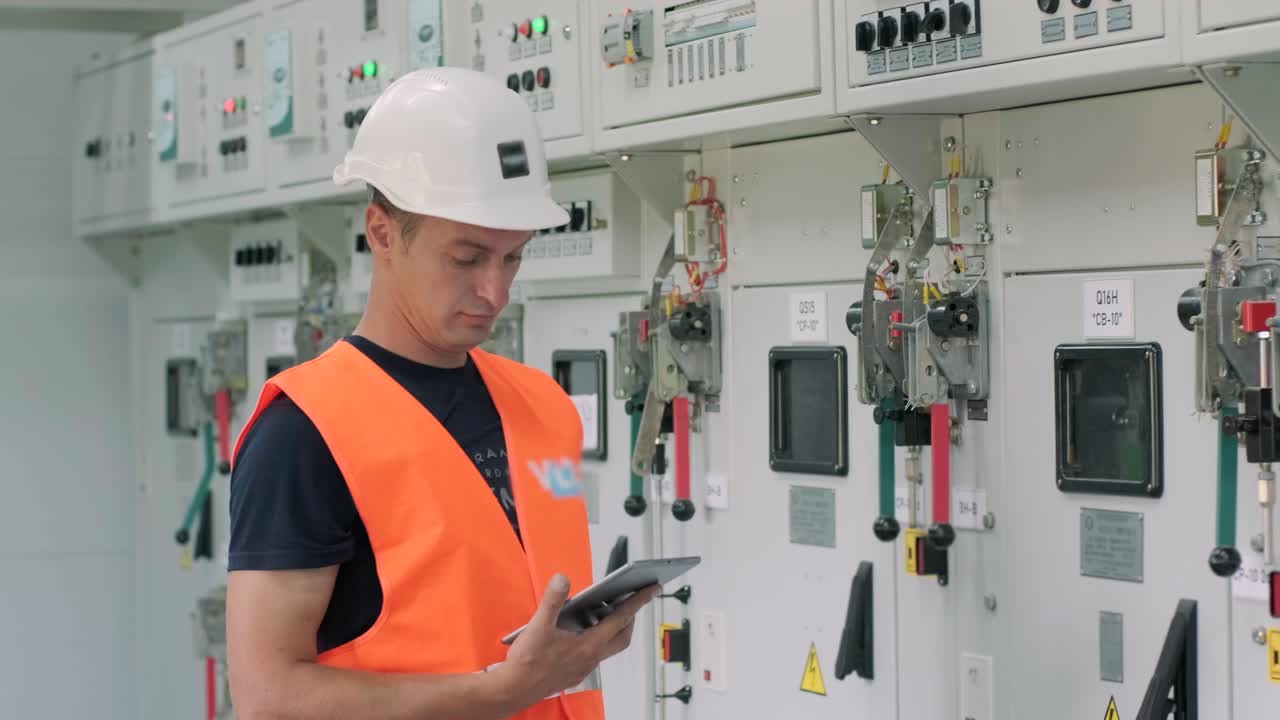 el ingeniero eléctrico que trabaja comprueba la tensión de corriente eléctrica y la sobrecarga en la parte delantera del gabinete del centro de carga o de la unidad de consumo para el mantenimiento en la sala principal del sistema de distribución de energía.