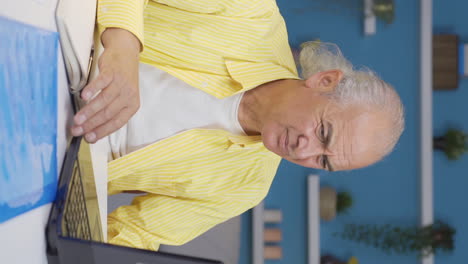 Vertical-video-of-Home-office-worker-old-man-has-trouble-focusing.