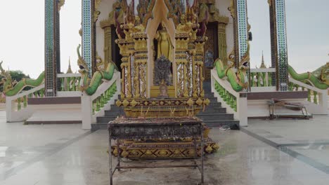 Thai-temple-details-dolly-shot-close-up-with-Buddha-statue-and-incense-sticks-standing-outdoors