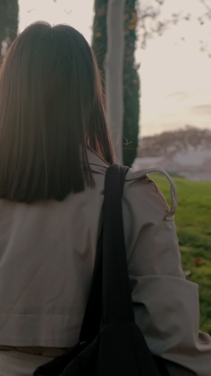 Woman in trench coat walking in a park