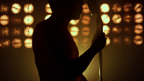 singer performing song firely on stage closeup. silhouette unknown man performer