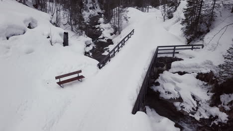 vista aérea de uma pequena ponte sobre um riacho em um vale nevado nos alpes, kleinwalsertal, áustria