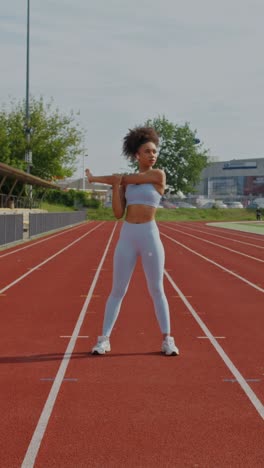 mujer estirándose en una pista de atletismo